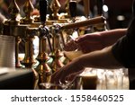 closeup of a bartender pouring a blonde double malt beer in tap behind the bar counter