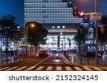Small photo of Osaka, Japan - May 1, 2022: Single motorbike approaches traffic light in front of JR Osaka Station at night
