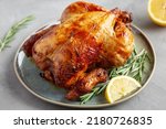 Small photo of Homemade Lemon and Herb Rotisserie Chicken on a Plate on a gray background, side view.