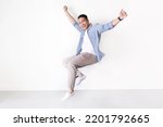Smiling Asian man full length in casual shirt floating in the air with copy space. Asian man full length in standing shot on isolated.