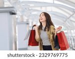 Cheerful Asian woman holding shopping bags.Beautiful Asian woman in casual style shopping in the city.