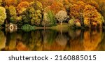Panorama of the reflection of the autumn foliage of the forest in the water. Autumn forest river reflection. Autumn forest reflected in river water. Autumn river reflection