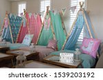 Small photo of Blue, green, pink and lama teepee's all set up for a sleepover birthday party. There is also fairy lights, bunting and face masks .