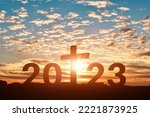 Silhouette of Christian cross with 2023 years at sunset background. Concept of Christians new year 2023