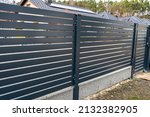 Modern anthracite panel fencing, visible spans and a fence foundation connector, view from the garden.