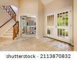 Small photo of Mid century craftsman house interior living room foyer home office with wood panel walls staircase creative wooden railings stone fireplace in warm white tones and orange accent colors