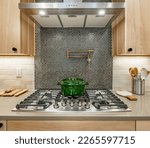 Small photo of kitchen interior with butcher block countertops penny tile stainless appliances green cast iron pot on stove and light wood tone cabinets