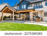 Small photo of classic home exterior with cement tile patio deck stone entry wide front door patio with chairs and a fire pit area with trees and bbq seating dining on a bright sunny colorful day blue sky