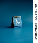 Small photo of Happy new year 2023 background. 2023 numbers year with target icon on blue small desk calendar cover standing on blue background, vertical style. Business goals and success concepts.