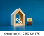 Small photo of Home tax concept. Resident rate, real estate, property and building annual taxation. Big percentage icon in modern white wooden house model and up and down arrow on flip wood block on blue background.