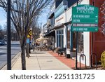 Small photo of PINEVILLE, NC, USA-15 JANUARY 2023: A view down Main Street sidewalk, with sidewalk diners at Margaux's an Christie's on Main. Sunny, blue sky day. Directional sign to important locations in town.