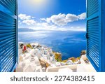 Hillside view through an open window with blue shutters of the caldera, sea and white village of Oia on the island of Santorini, Greece.