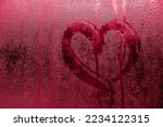 Heart painted on misted glass. Valentines day, love symbol on frozen glass in winter. Selective focus. Color of the year 2023 - Viva Magenta