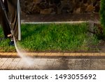 Close up photo of a man hands, cleans a tile of grass in his yard. High pressure cleaning