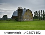 Small photo of Silo Alongside aLarge Gambrel Barn on a Rainy Day in a Green Pasture