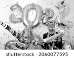 attractive man and young woman celebrating new year 2022 at home quarantine. boy and girl with hands up. big number balloons. silvester party. december 31. lockdown. confetti falling. january 1.