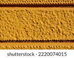 Small photo of stipple finish yellow stucco exterior elevation detail with rough texture. deep grove pattern. surfaces, textures and patterns concept. facade macro detail. extreme closeup. building and architecture