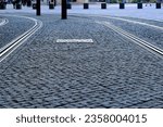 Small photo of gray cobblestone cube granite pavement. rectangular shaped loosely set stones. empty joints. steel tram rails embedded. street and walkway paving design concept. diminishing perspective view