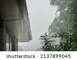 Small photo of Roof gutter overflow in the heavy rain. Rain water cascading over the gutter.
