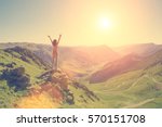 The young girl raised her arms up to the sun on a background of mountains 
