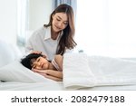 Small photo of Asian loving parents take care of sleeping daughter in bedroom at home. Attractive happy family, beautiful mother puts blanket on comfortable asleep napping little baby kid on bed in morning in house.