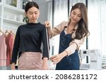 Small photo of Asian tailor woman measure customer's body to making her new clothes. Attractive female fashion designer dressmaker working and design new fashion collection for customer in tailoring atelier workshop