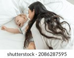 Small photo of Caucasian loving mom play with cute baby boy child on bed in bedroom. Happy family, attractive beautiful caring young mother ticklish on toddler son enjoying activity relationship in morning in house.