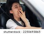 Small photo of Asian beautiful woman yawned and fall asleep while driving in a car. Attractive girl buckling safety seat belt inside vehicle feel sleepy and tired while driving for long time alone. Sleep deprivation