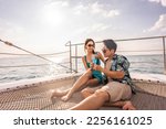 Small photo of Asian beautiful couple drinking champagne while having party in yacht. Attractive man and woman hanging out, celebrating anniversary honeymoon trip while catamaran boat sailing during summer sunset.