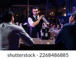Small photo of Caucasian profession bartender making a cocktail for women at a bar. Attractive barman pouring mixes liquor ingredients cocktail drink from cocktail shaker into the glass at night club restaurant.