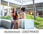 Asian beautiful two women shopping goods outdoor in department store. Attractive young female friend holding shopping bags then walking with happiness enjoy purchasing in shopping mall center together