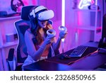 Small photo of Asian young Esport woman gamer use technology VR glasses and play game. Attractive beautiful female gaming player wear virtual reality headset, feel excited and enjoy broadcast live stream online game
