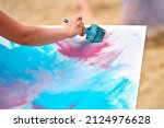 Amateur painter drawing picture on white canvas at outdoor art workshop. Woman artist hands with paintbrush painting new picture, outdoor art exercise, painting performance