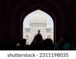 Small photo of Archway of main gateway in Taj Mahal entrance with tourists silhouettes, view to Taj Mahal marble mausoleum landmark through arch, massive influx of tourists in India, Taj Mahal tourist season