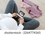 Small photo of A pregnant woman is making recheck and prepare by mobile phone for new born. Caesarean section is a way for pregnant women to know a due date. Concept of preparing for mother.