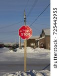 Small photo of Bilingual octagon red stop sign with in Inuktitut (Syllabic), and English snow on the ground