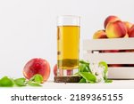 Apple juice. Full glass of natural apple juice on a wooden podium with red apples and blossom branche on a white background with copy space. Summer natural drink. Soft focus stile