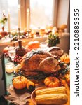 Small photo of Classic USA Thanksgiving day dinner with holiday autumn decor and candles. Family dining room table set with delicious golden roasted turkey on platter garnished rosemary and fresh small pumpkins