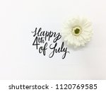 Happy 4th of July hand-lettered on a piece of white paper against a white background with a white daisy on the right side of it flatlay
