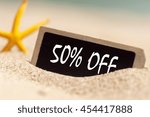 wooden board on sunny sandy beach  with text 50% off