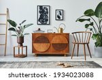 Stylish scandinavian composition of living room with design commode, black mock up poster frames, chair, wooden stool, book, decoration, plants and personal accessories in modern home decor.