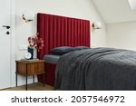 Small photo of Minimalistic elegant bedroom interior with red bed, grey bedclothes and wooden furniture. Glamour style inspiration. Template.
