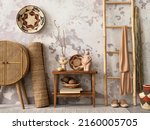 The stylish ethnic composition at living room interior with design, colorful baskets, rattan sideboard and elegant personal accessories. Grey concrete wall. Cozy apartment. Home decor. 