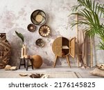 The stylish ethnic composition at living room interior with design colorful baskets, rattan sideboard and elegant personal accessories. Grey concrete wall. Cozy apartment. Home decor. 