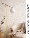 Small photo of Minimalist composition of elegant and outstanding space with white boucle armchair, lamp, plaid and personal accessories. Cozy home decor. Template.
