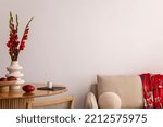Small photo of Warm and cozy interior of living room space with wooden table, beige sofa, red flowers, kimono, rattan chair, decoration and elegant personal accessories. Copy space. Home decor. Template.