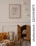 Small photo of Cozy kids room interior with mock up poster frame, plush toys, orange pillow, braided armchair, rattan sideboard, clouds garland, beige wall with stucco and personal accessories. Home decor. Template.