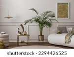 Warm composition of living room interior with boucle armchair, sofa, plant in gold pot, green pillows, round rug, stylish coffee table, wall with stucco and personal accessories. Home decor. Template.