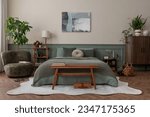 Creative composition of bedroom interior with mock up poster frame, green bedding, wooden side table, stylish bench, beige rug, plants, basket, lamp and personal accessories. Home decor. Template. 

