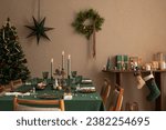 Interior design of warm dinning room interior with christmas table, wooden console, christmas gifts, gingerbread, candle, star on wall christmas wreath and personal accessories. Home decor. Template.